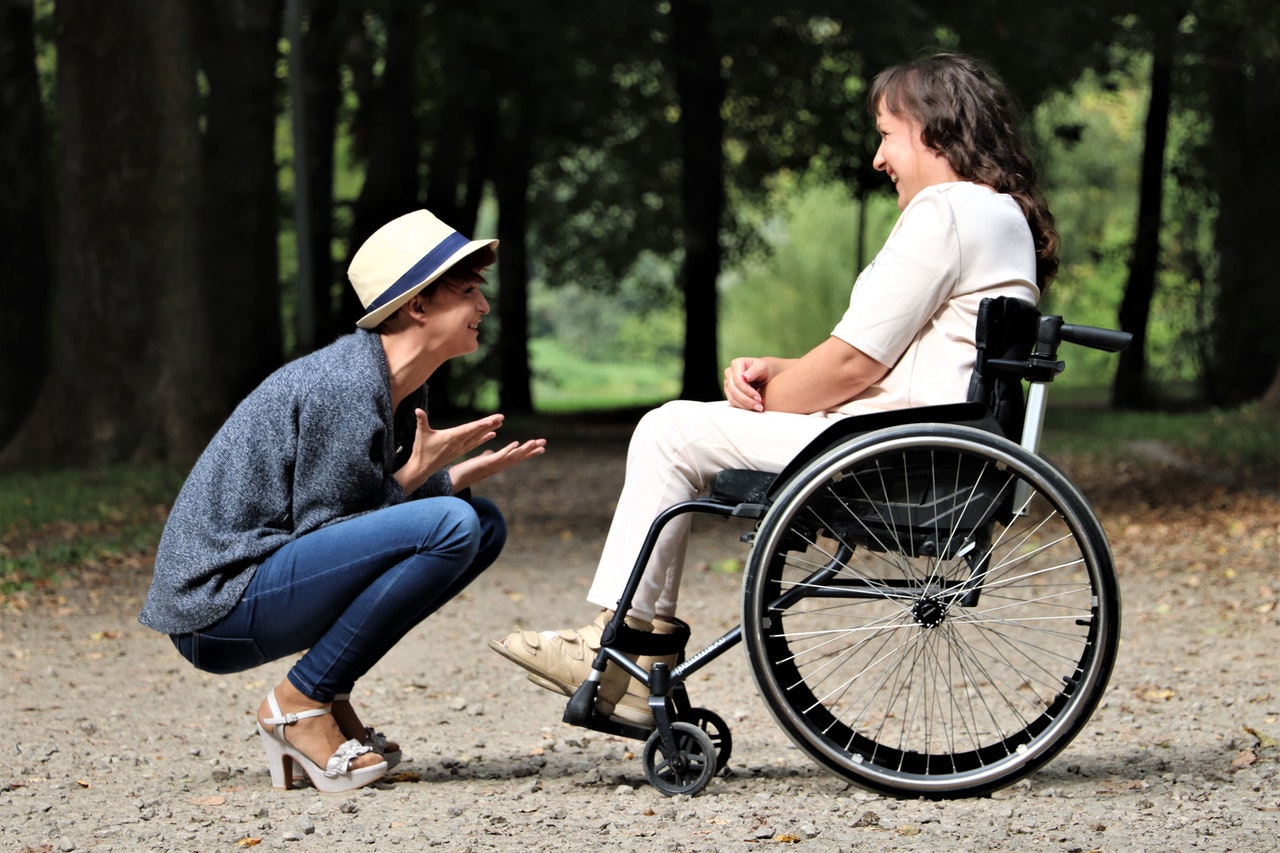 Dve ženy z toho jedna na invalidnom vozíku sa rozprávajú a smejú