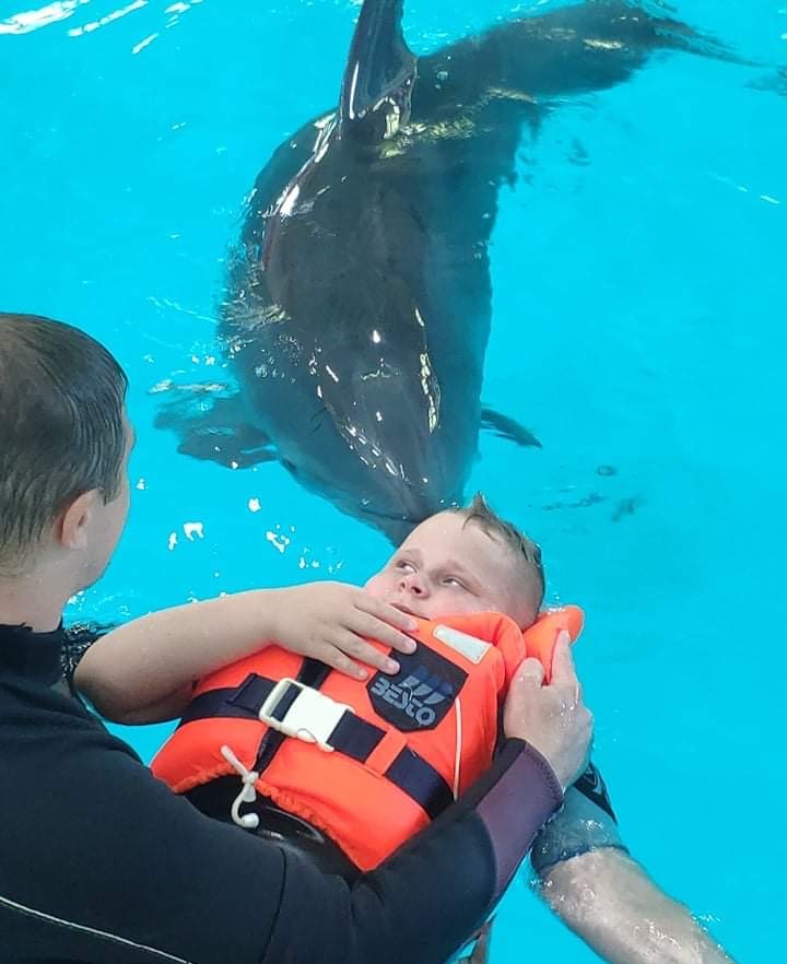 Delfínoterapia chlapca, ktorému pomáha dospelý