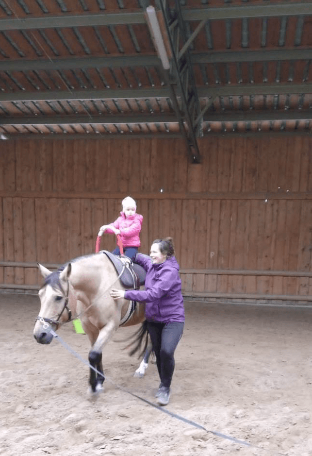 Žena vedúca koňa, na ktorom sedí dieťa